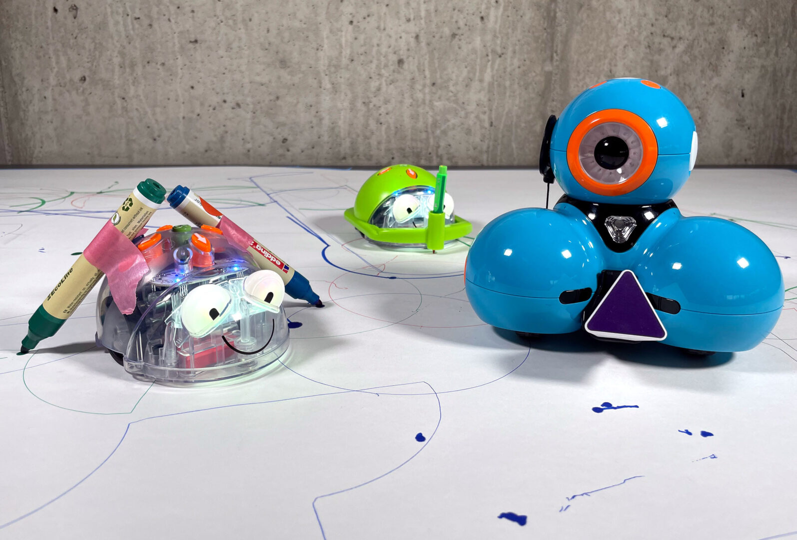 Zwei verschiedene Roboter haben Stifte montiert, mit denen sie ihren Weg auf einem Blatt Papier nachzeichnen.