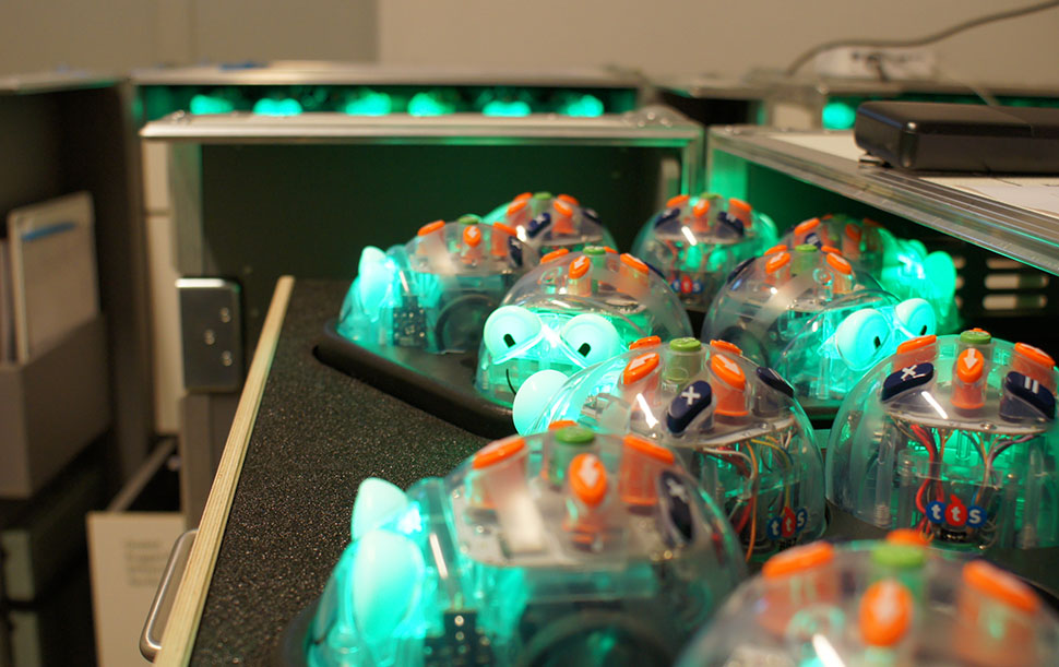 Zu sehen sind viele Blue-Bot Lernroboter, die grün leuchten.