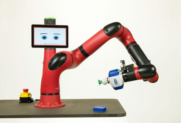 Der rote Roboterarm Cobot Sawyer ist auf einem schwarzen Tisch montiert. Vom zentral angebrachten Tablet blickt er mit Augen und Brauen in die Kamera.